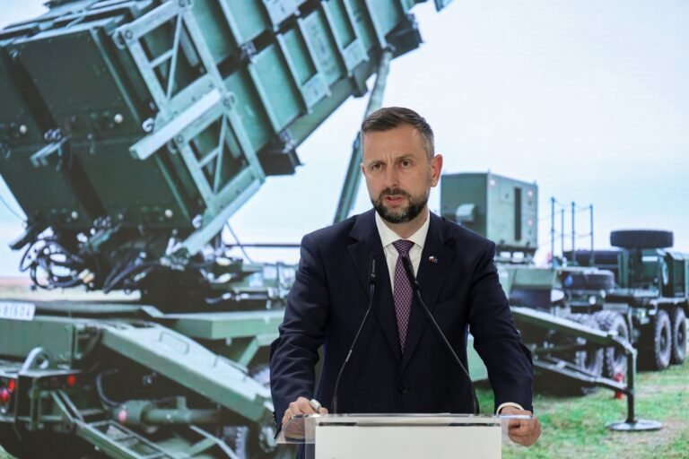 Портрет Владислава Косіняка-Камиша, міністра оборони Польщі, що виступає з промовою на фоні польського прапора.