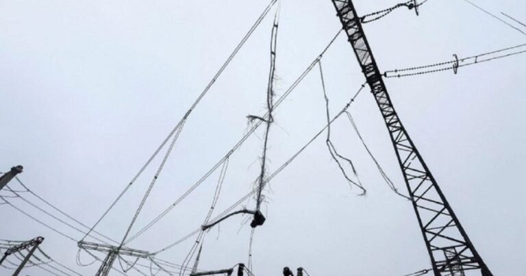 Українська багатоповерхівка в темряві після російської атаки, вікна поодиноко світяться, місто виглядає нічним через знеструмлення.